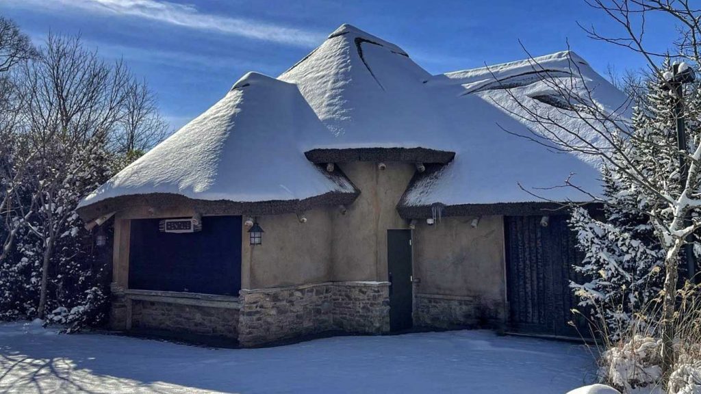 Picture of a building with a synthetic thatch roof in heavy snow.