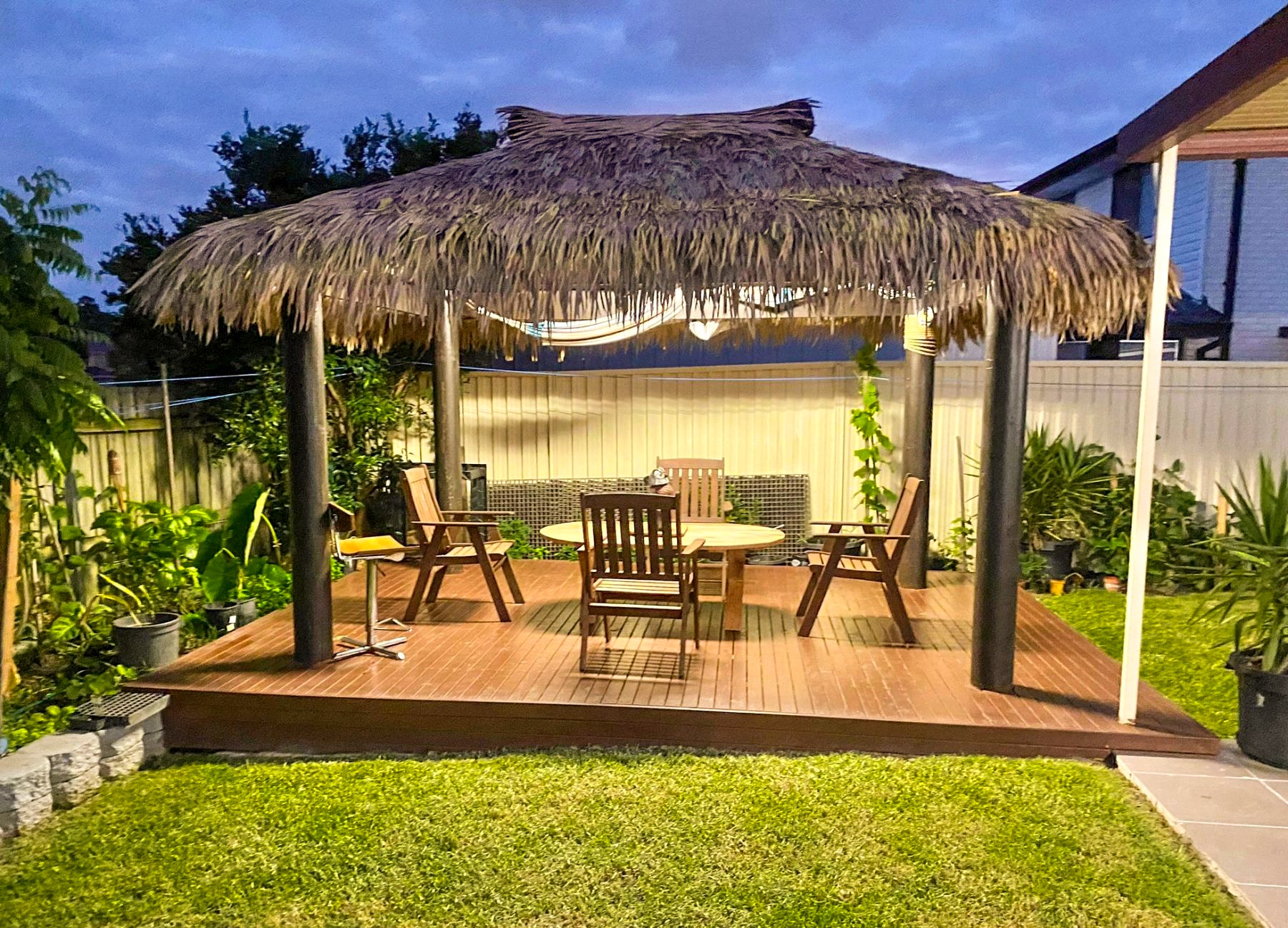 Backyard palapa with synthetic thatch at night.