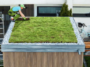 A roofer installing grass on a roof to create a green roof.