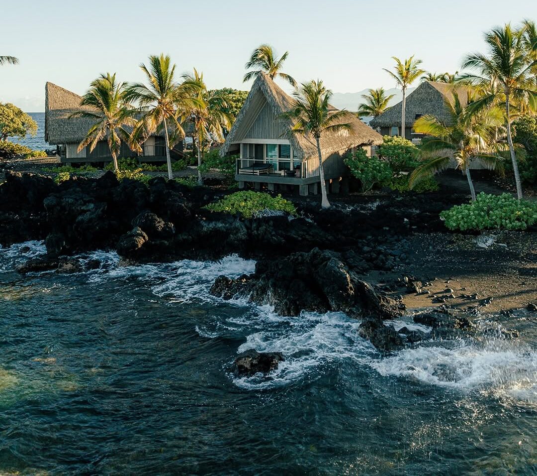 Kona Village Resort hale bungalows with custom Endureed engineered thatch roofing on Hawaii's Kona coastline at golden hour &mdash; luxury resort thatch roofing by Endureed