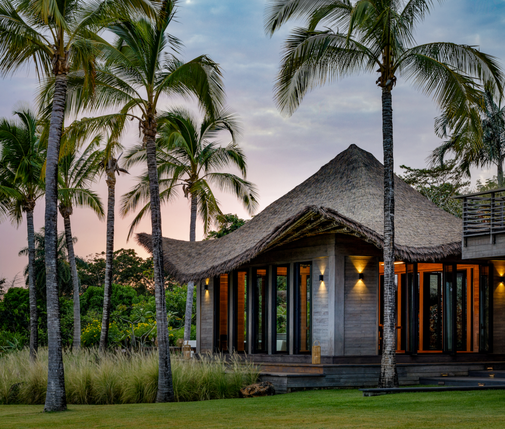 Casa Loro thatched pavilion at dusk Pedasi Panama, Endureed bespoke engineered thatch roofing glowing under ambient exterior lighting, custom synthetic thatch blend for luxury private tropical estate