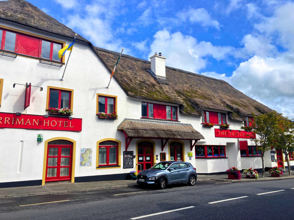 Full street view of the Marriman Hotel and The Thatch Bar, Ireland &mdash; a classic Irish thatched hospitality venue with white render, red signage, flower boxes, and a traditional reed roof &mdash; representing the commercial hospitality segment Endureed Somerset Premium is engineered to serve.