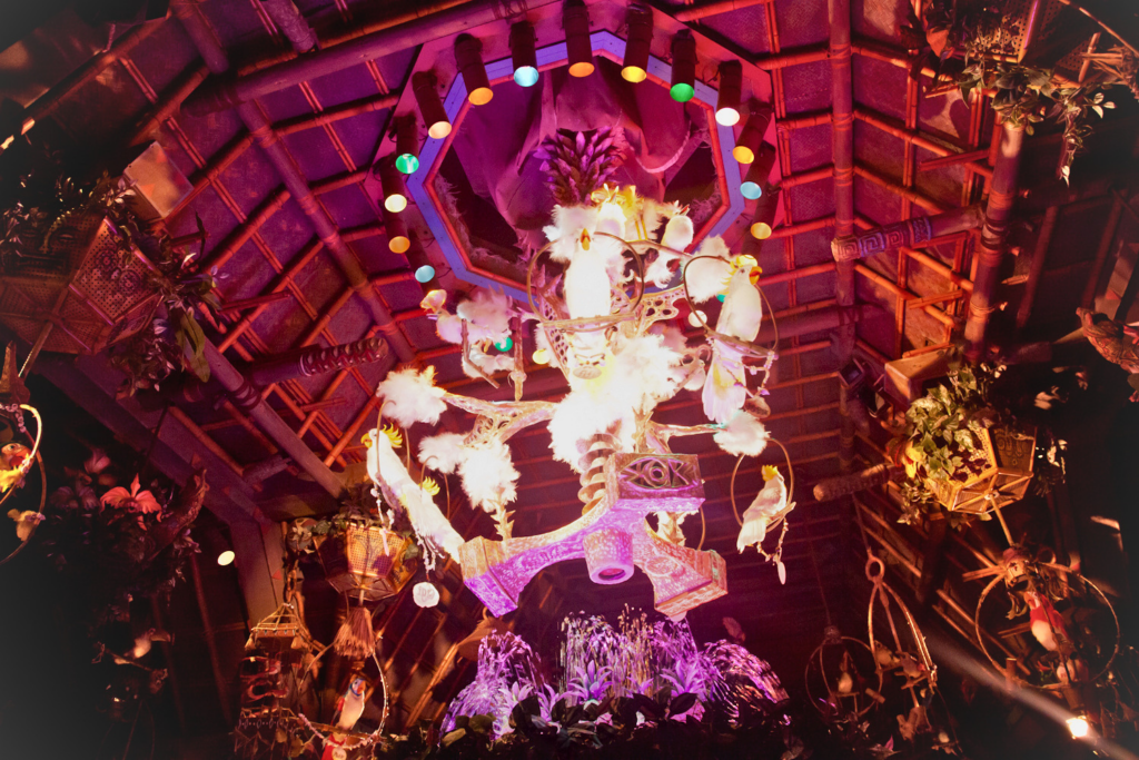 Interior bamboo ceiling framework inside Disneyland Adventureland thatched structure &mdash; engineered roof support structure visible beneath Endureed Premium Dominica synthetic thatch installation