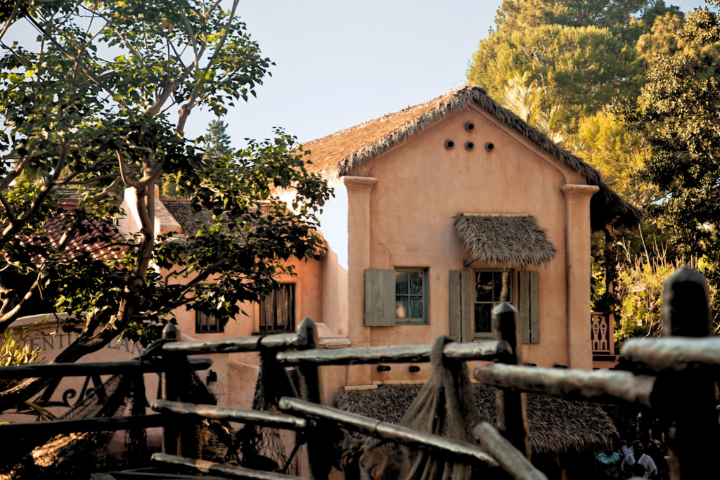 Endureed Premium Dominica synthetic thatch roof and awning on Adventureland building at Disneyland Anaheim &mdash; thatch applied to stucco structure with natural wood fence foreground