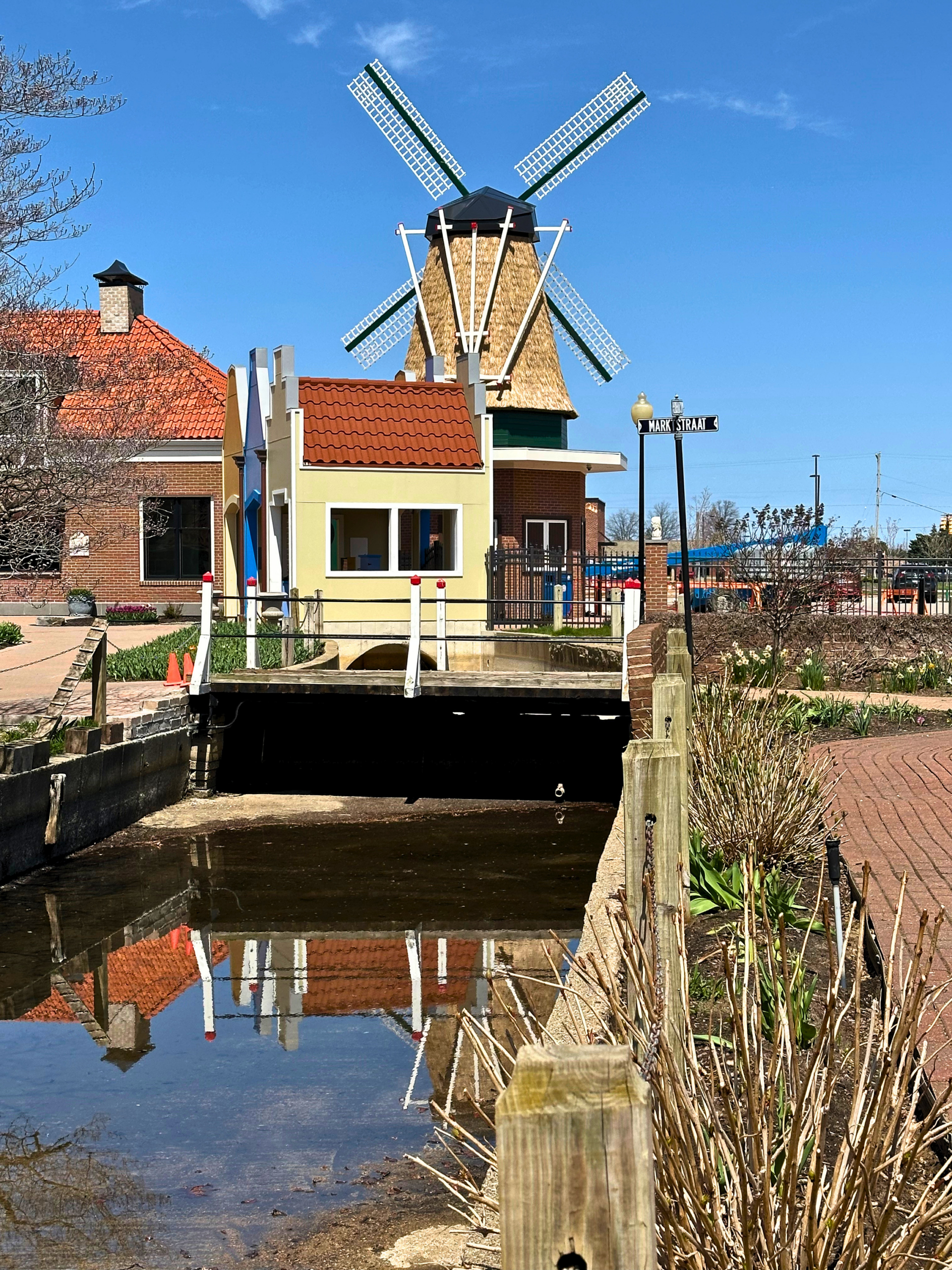 Endureed Somerset synthetic thatch windmill cladding at Nelis Dutch Village Holland Michigan reflected in canal, premium engineered thatch for cultural theme park landmark architecture in four-season climate