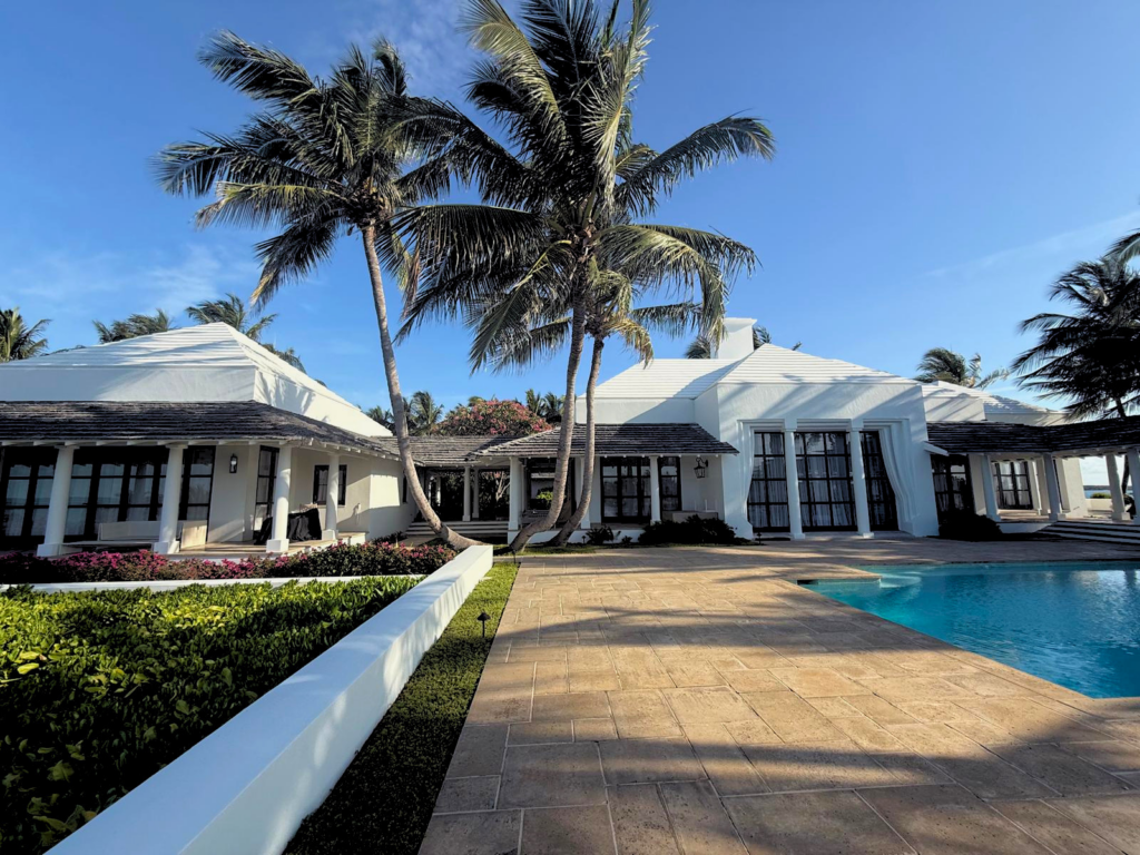 Endureed Kilimanjaro engineered thatch roof on white stucco luxury residence surrounded by palm trees and tropical landscaping, Bahamas