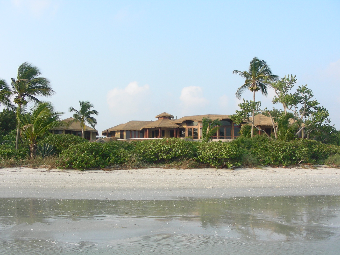 Baum residence viewed from Sanibel Island beach, Endureed Premium Bali thatch roof visible against Florida sky