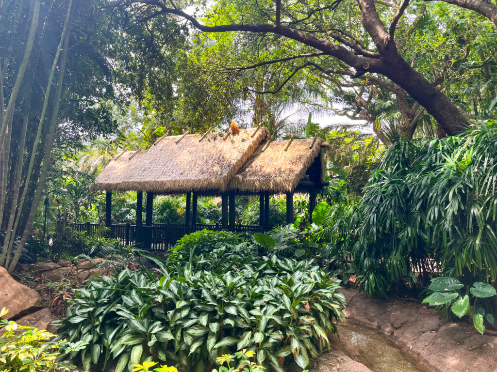 Endureed engineered thatch open-air shelter at Discovery Cove Orlando, synthetic thatch roofing for immersive tropical theme park landscape structure surrounded by lush jungle plantings