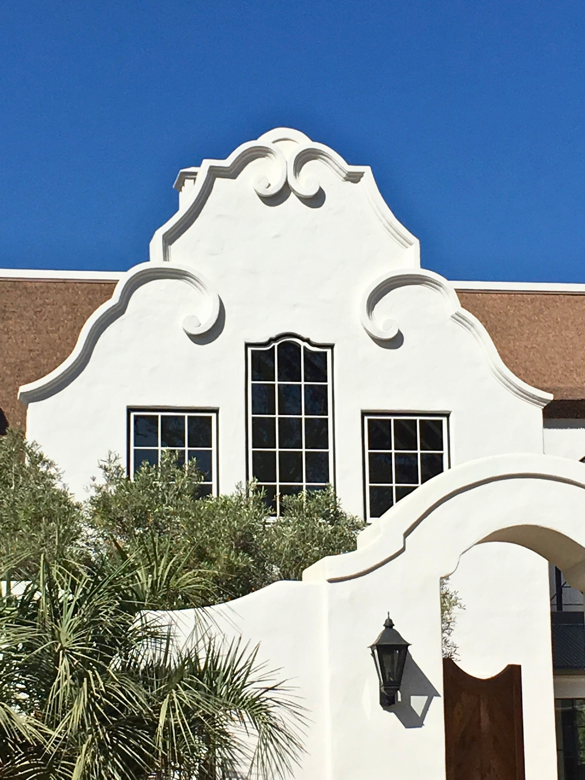Cape Dutch gable architectural detail at Dean's Grange Malibu California &mdash; ornate curved white parapet with Endureed Premium Kilimanjaro synthetic thatch roof visible at roofline flanking decorative scrollwork and arched windows