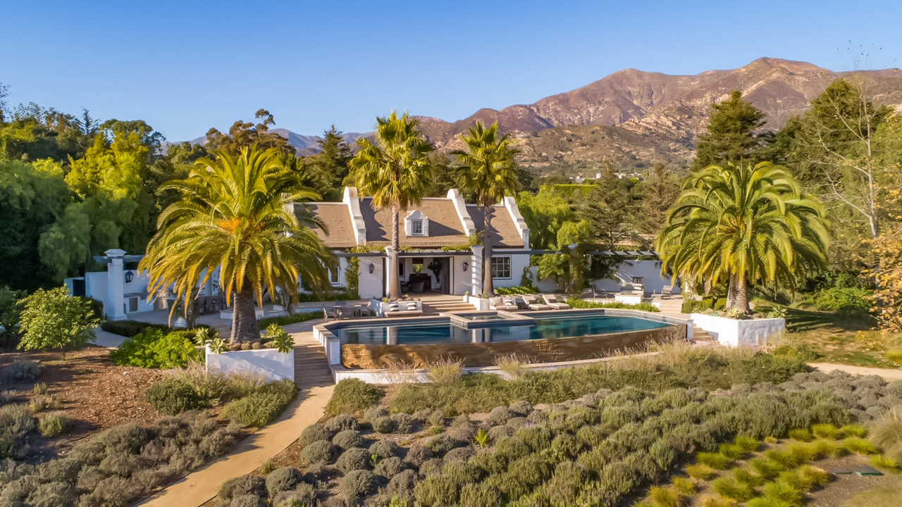 Aerial drone view of Dean's Grange private estate in Malibu California featuring Endureed Premium Kilimanjaro synthetic thatch roofing — luxury Cape Dutch residence with engineered thatch roof, infinity pool, and Santa Monica Mountains panorama