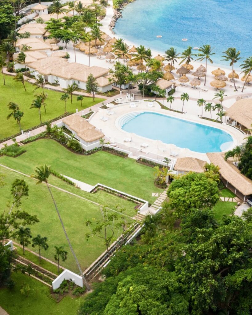 Aerial view of Sugar Beach resort St. Lucia featuring Endureed Performance Palm synthetic thatch across villa rooftops beach cabanas and umbrella structures &mdash; engineered thatch resort installation with pool turquoise Caribbean Sea and lush grounds