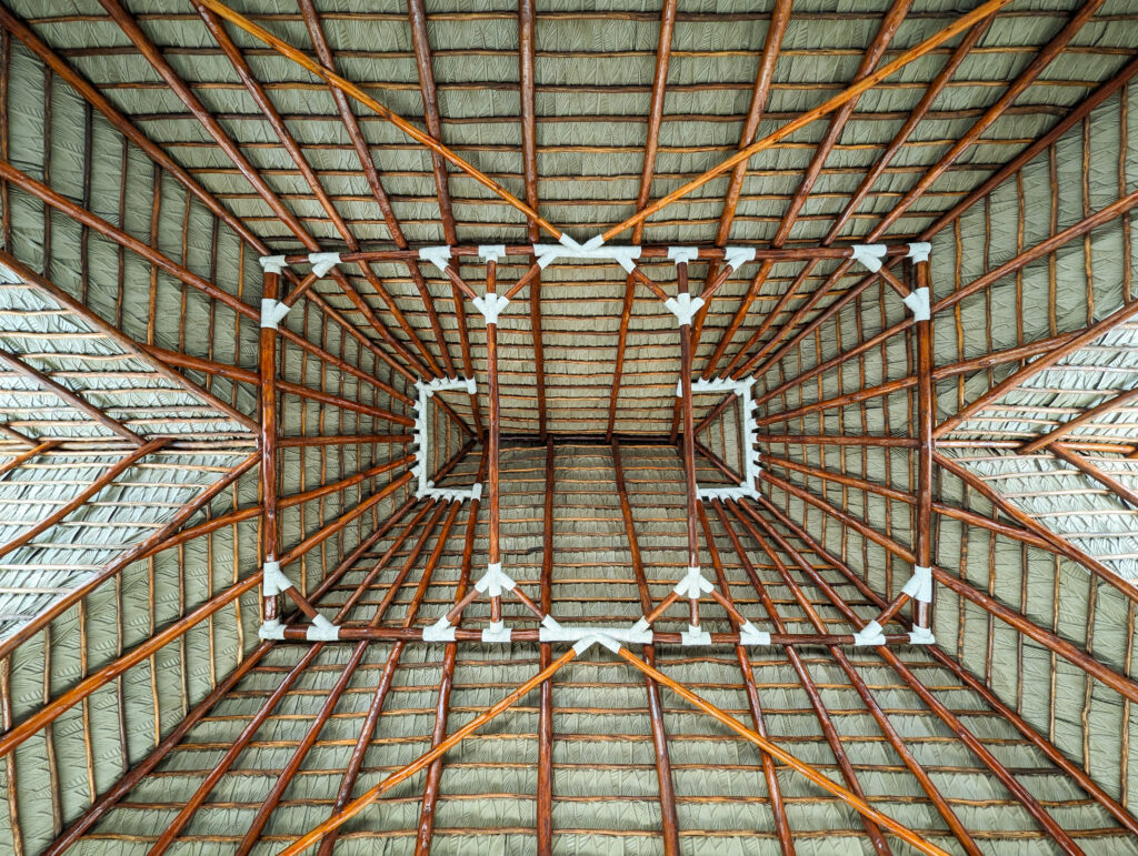 Symmetrical view looking straight up into a Performance Palm synthetic thatch roof structure at Casa De Verano in Guatemala, showing the radial wood batten framework and lashed joinery detail.