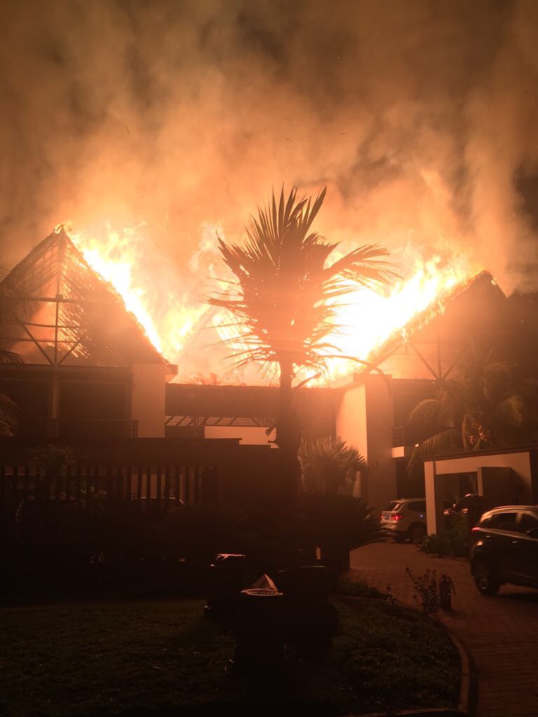 Natural thatch roof fire engulfing a beachfront home in Guatemala, showing the fire risk that led the Marsicovetere family to rebuild with engineered thatch