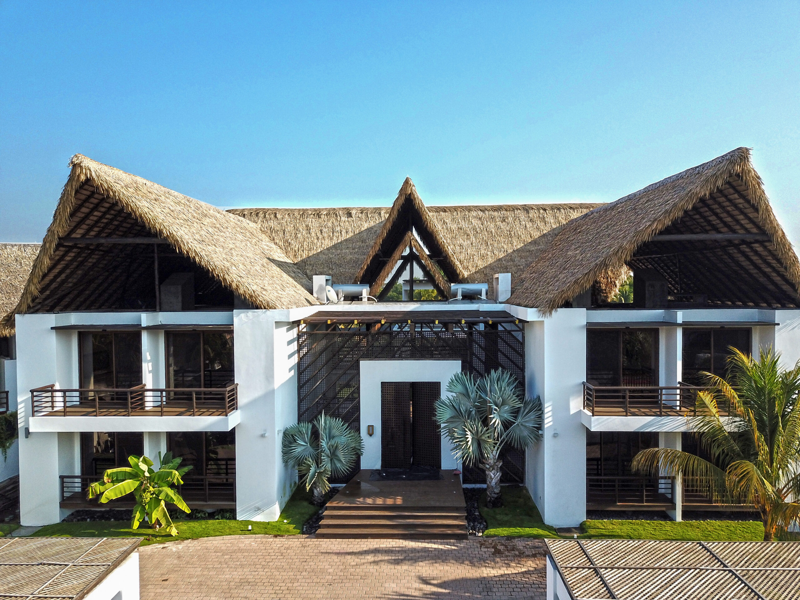 Side aerial view of the completed Marsicovetere beach house roofline showing Endureed Performance Palm engineered thatch across multiple roof sections