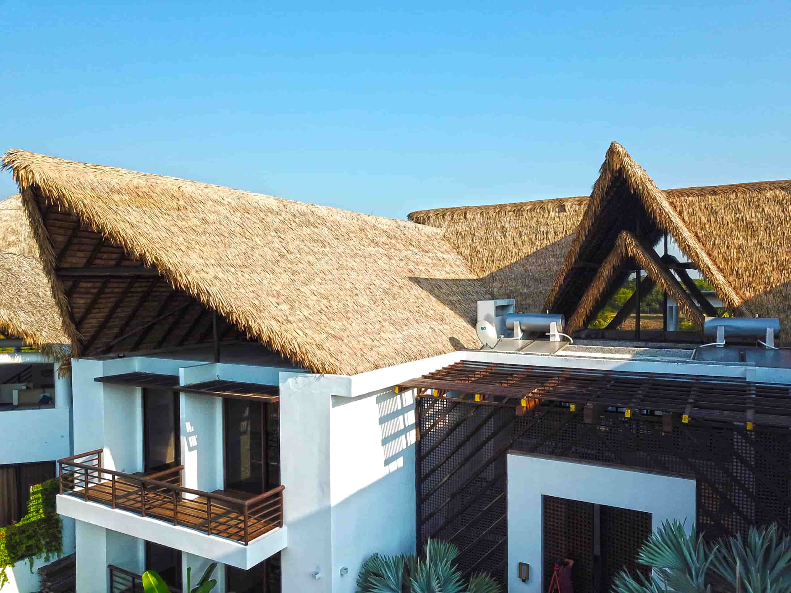 Drone front view of the Marsicovetere family home in Guatemala featuring engineered thatch roofing on a modern two-story white beach house